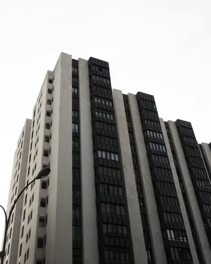 Scatto da un'angolazione bassa di un edificio alto e moderno con un motivo ripetuto di cemento grigio chiaro e finestre scure
