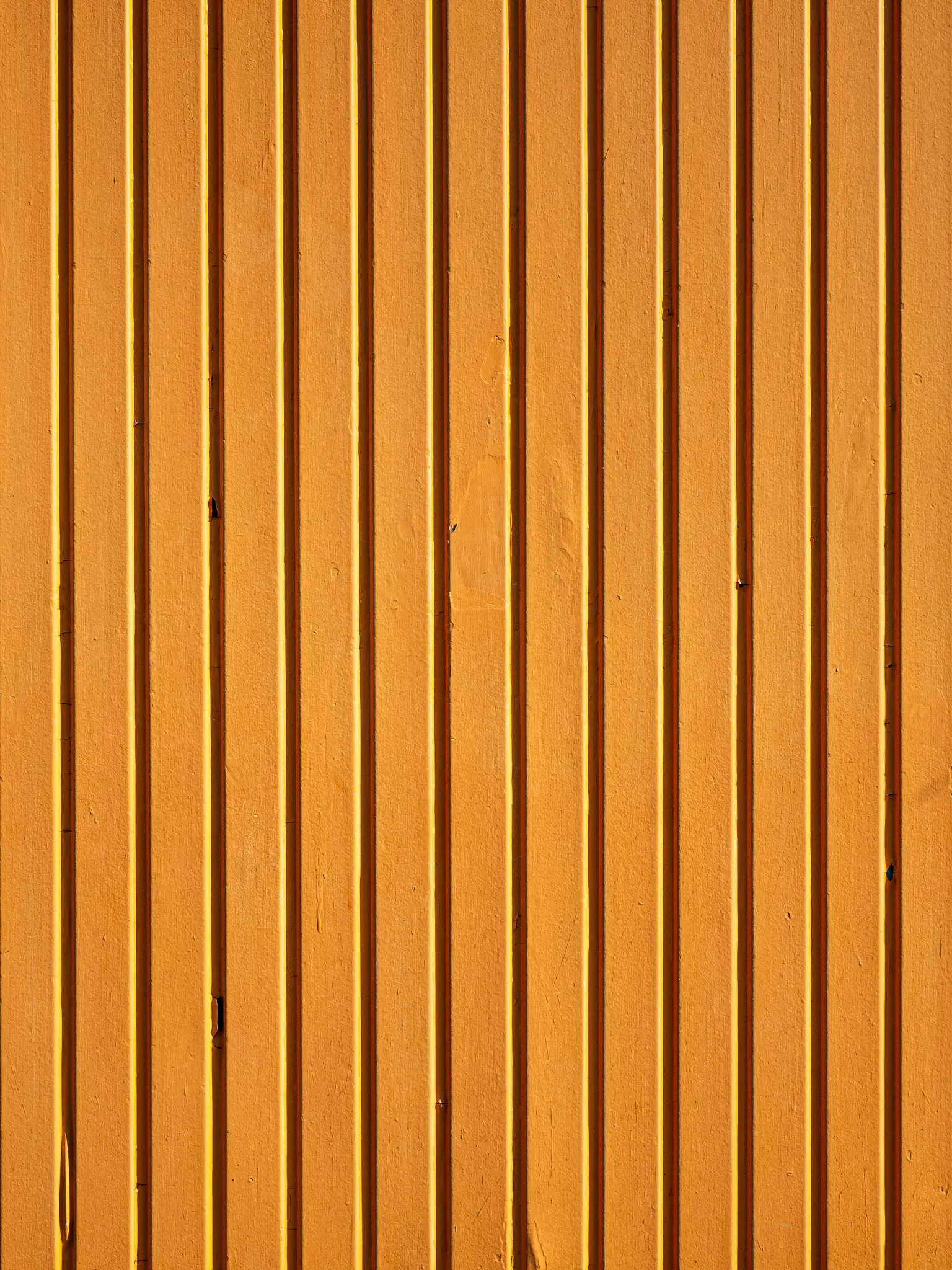 Una vista de primer plano, a fotograma completo, de una superficie de metal corrugado de color naranja brillante con fuertes