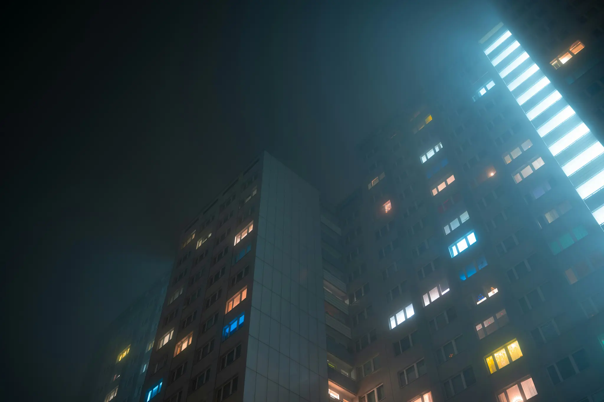 Una toma desde un ángulo bajo de múltiples edificios de apartamentos altos y grises por la noche, envueltos en una atmósfera