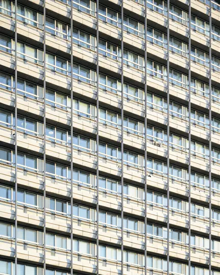 Una vista ravvicinata e frontale della facciata di un edificio moderno, con numerose finestre rettangolari e balconi.