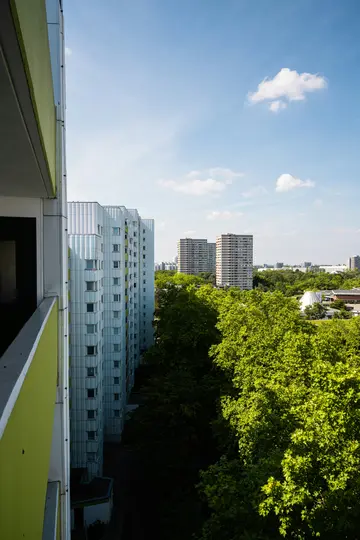 Una vista dall'alto da un balcone mostra una fila di edifici residenziali a più piani di colore grigio chiaro accanto a una