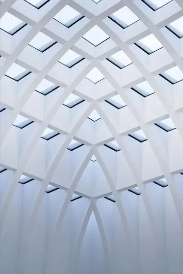 Eine abstrakte, nach oben gerichtete Ansicht einer modernen weißen Decke mit einem geometrischen Gitter aus quadratischen