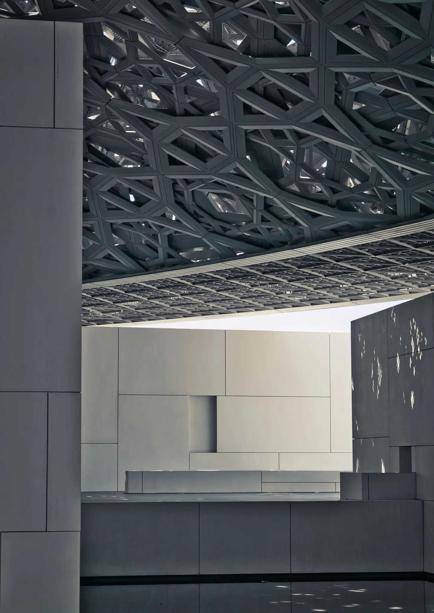 Eine detaillierte Ansicht moderner Architektur mit einem dunklen, kunstvollen geometrischen Dachmuster über hellen