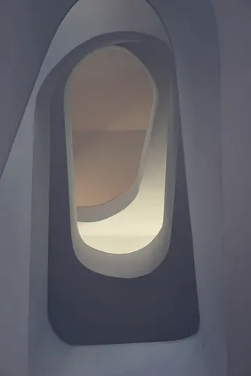 Ein minimalistisches Foto von gebogenen Architekturformen in Grau-, Blau-, Beige- und Cremetönen, die einen Tunnel-Effekt