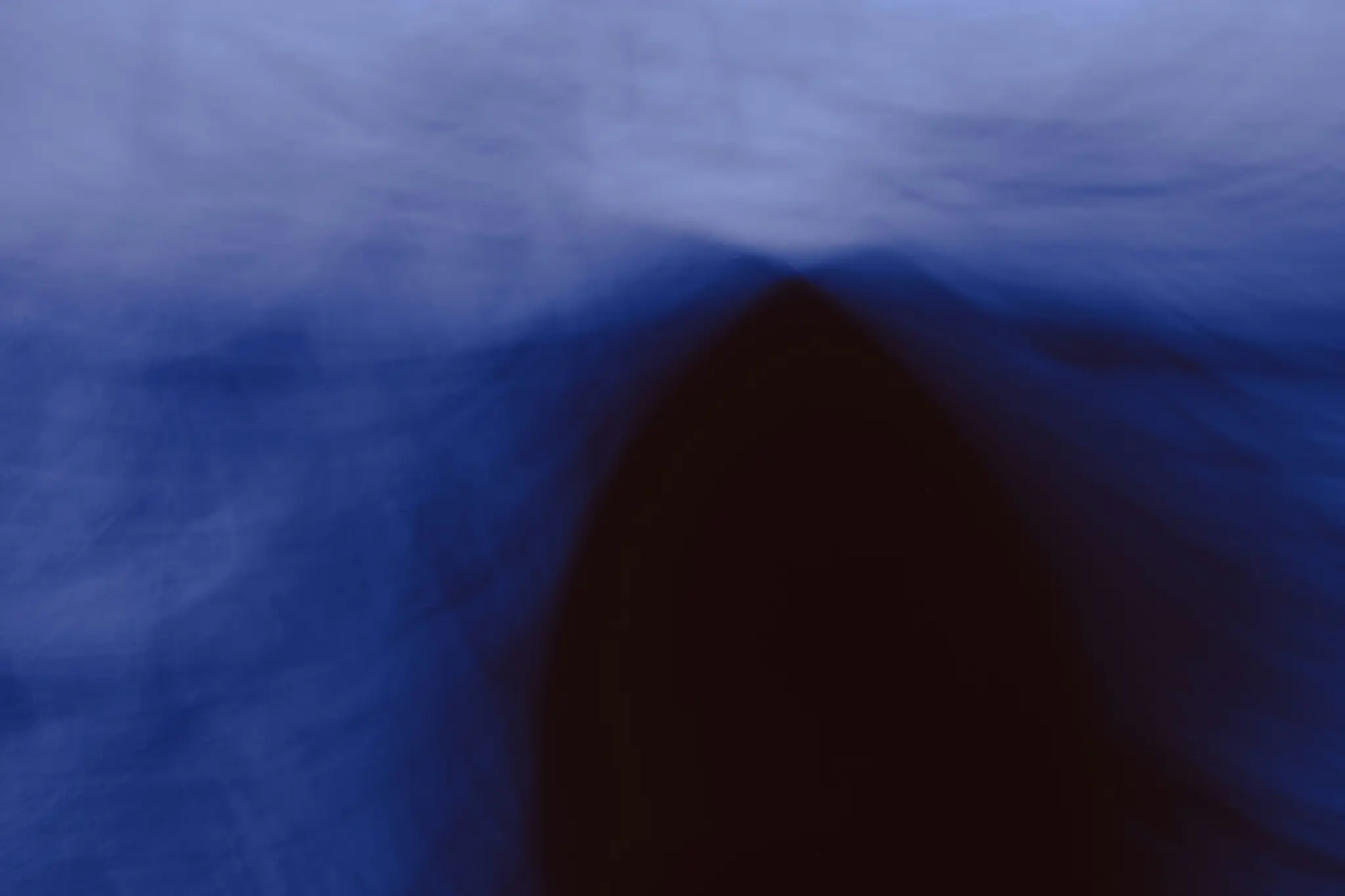 An abstract image featuring blurred shapes in shades of blue and dark brown, with a soft, ethereal quality.