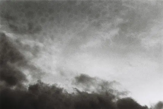 A black and white photo of a sky filled with dark, textured clouds, with a brighter area on the right side.
