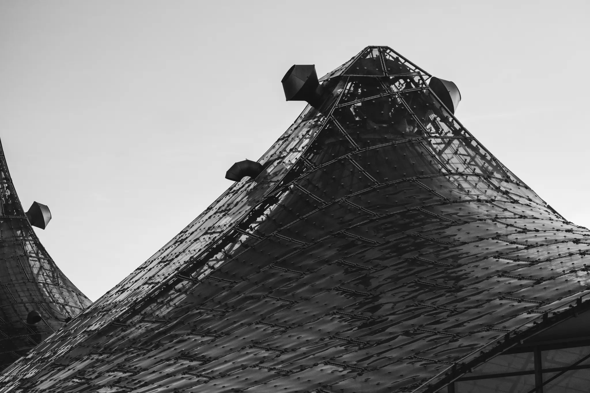 Et lavvinklet sort/hvid-billede af to store, mørke, teksturerede koniske strukturer med små ventilationsåbninger mod en lys