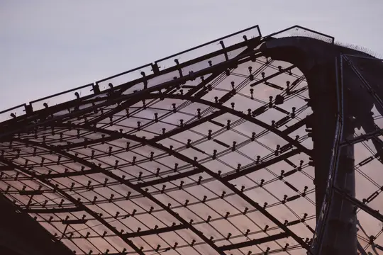A close-up shot of a modern glass and metal roof structure against a twilight sky with shades of purple and orange.