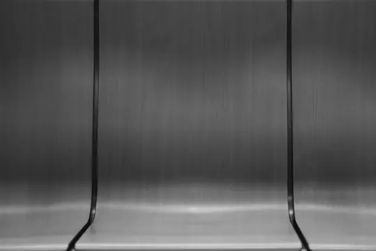 A black and white abstract photo of three curved wooden panels, possibly seats, with dark vertical dividers.