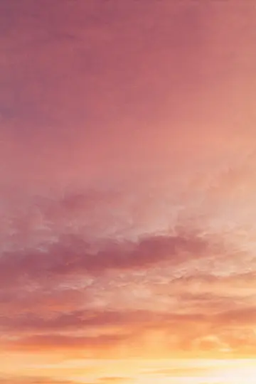 En levende himmel ved solnedgang, fyldt med bløde, dunede skyer i nuancer af pink, orange og gul.