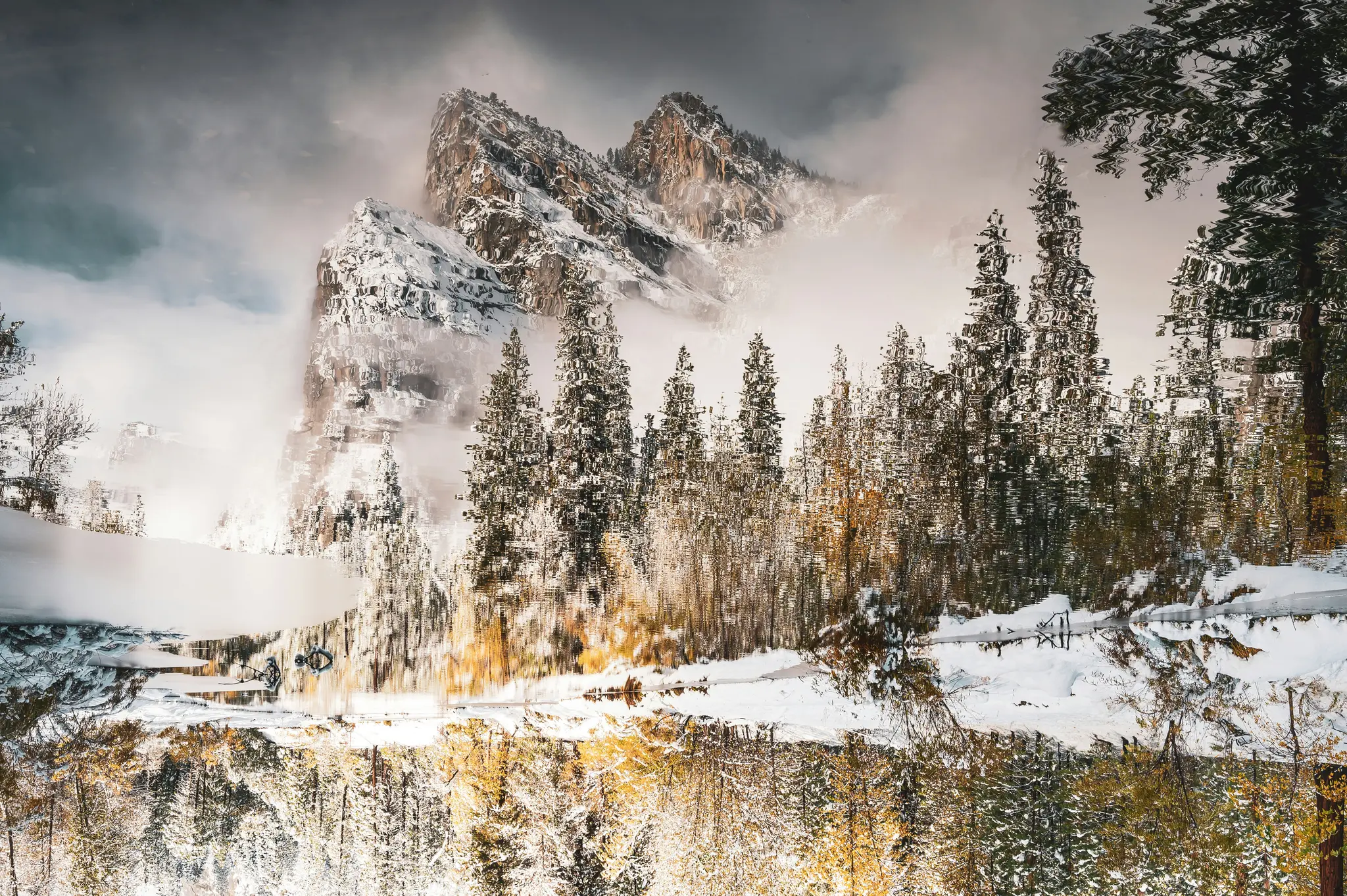 Een met sneeuw bedekte bergketen met dennenbomen wordt weerspiegeld in een rustig wateroppervlak, wat een omgekeerd
