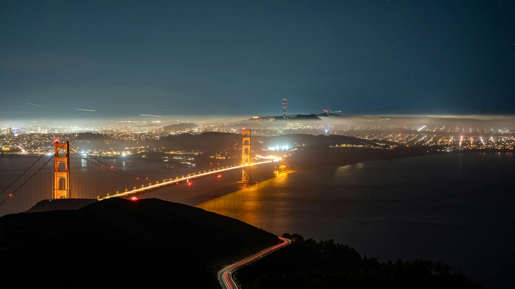 Een nachtopname met lange sluitertijd van de Golden Gate Bridge, verlicht met gouden licht, die zich uitstrekt over donker