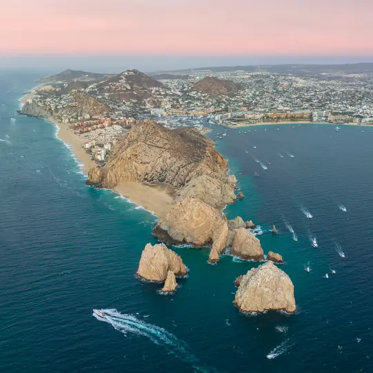 Une vue aérienne montre une ville côtière avec des bâtiments nichés entre les montagnes, une longue plage de sable et des