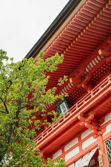 Une prise de vue en contre-plongée d'un bâtiment traditionnel japonais avec une façade rouge vif, des murs blancs et un toit