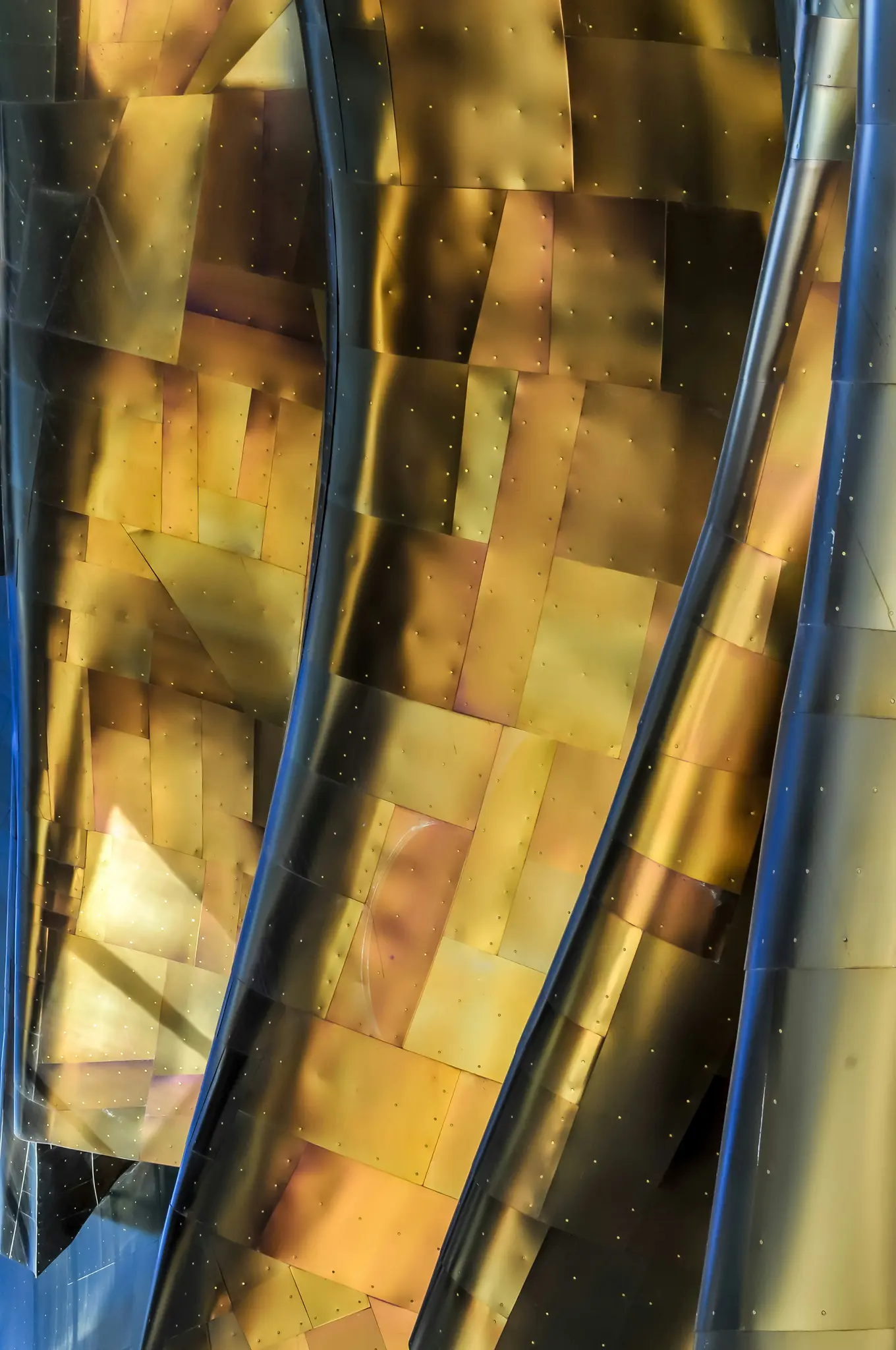 Nahaufnahme, abstrakter Blick auf die Außenseite eines Gebäudes mit einem Mosaik aus goldenen und bronzefarbenen