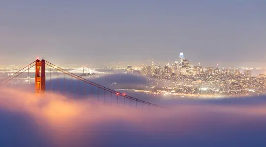 O imagine largă peisagistică a podului Golden Gate și a liniei orizontului din San Francisco la apus, parțial acoperită de
