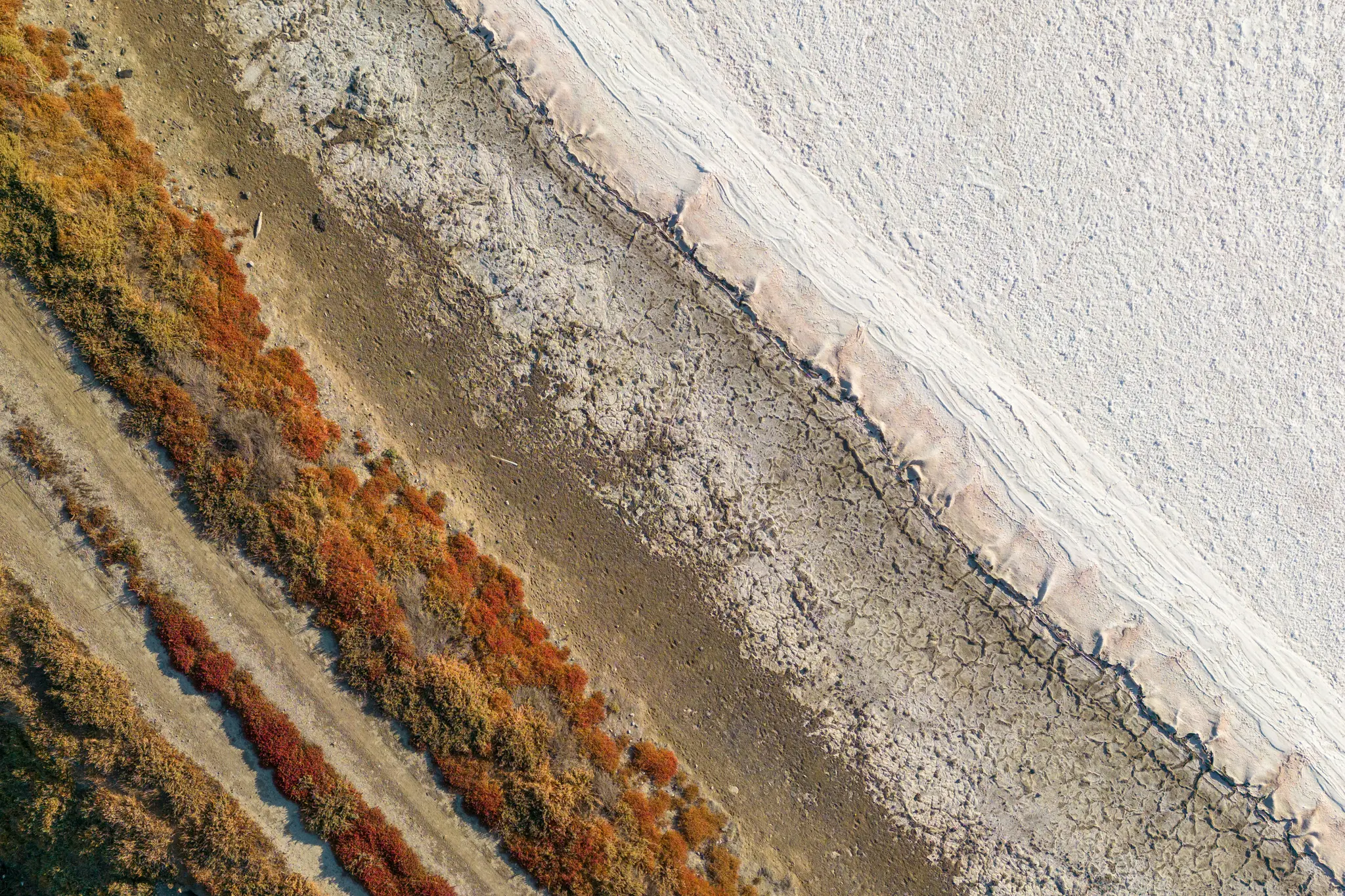 Una ripresa aerea, dall'alto, di un paesaggio arido. L'immagine è divisa diagonalmente in tre sezioni principali