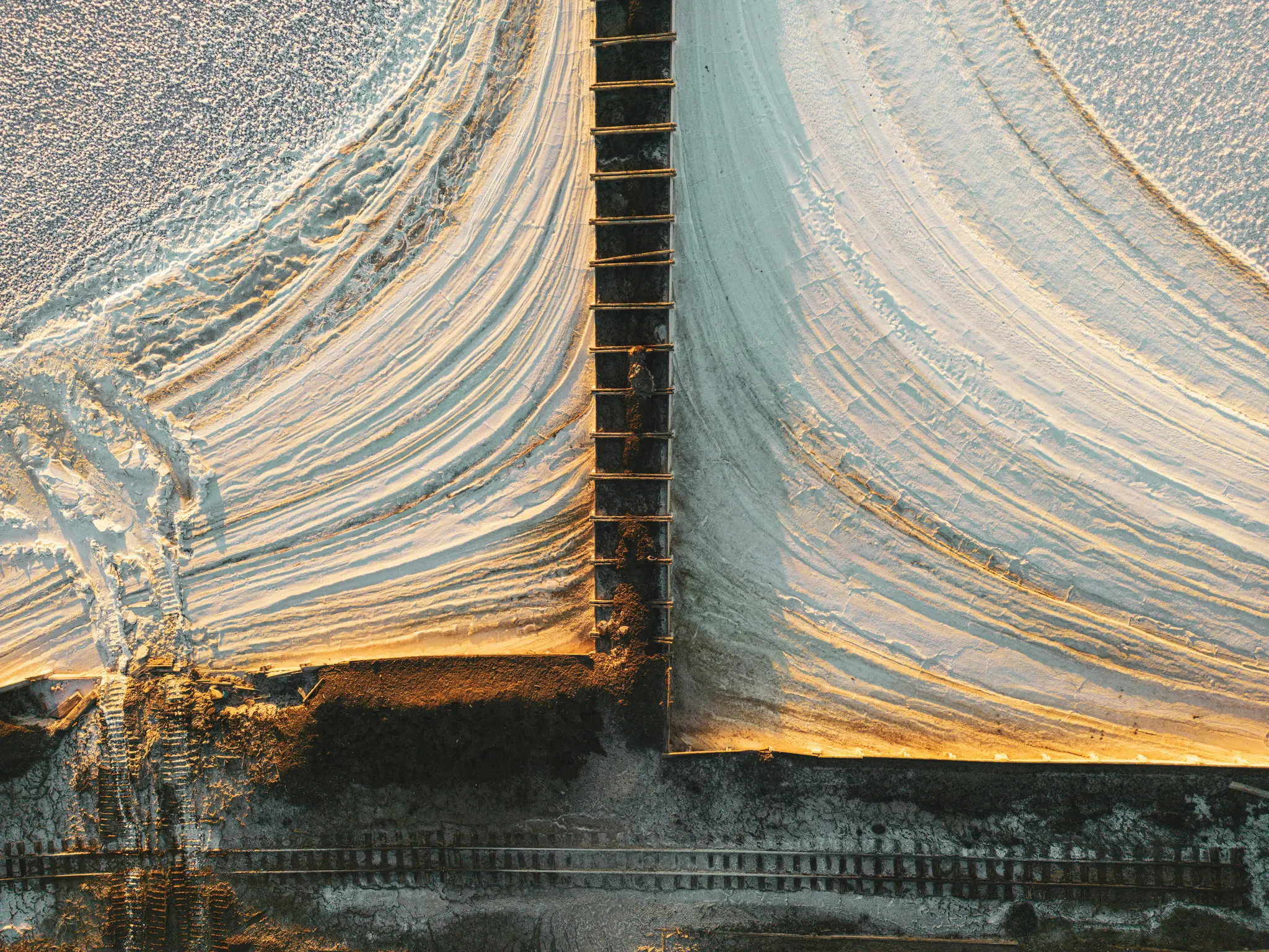 Een luchtfoto van bovenaf van een landschap met grote, witte heuvels met een getextureerd oppervlak, gescheiden door een