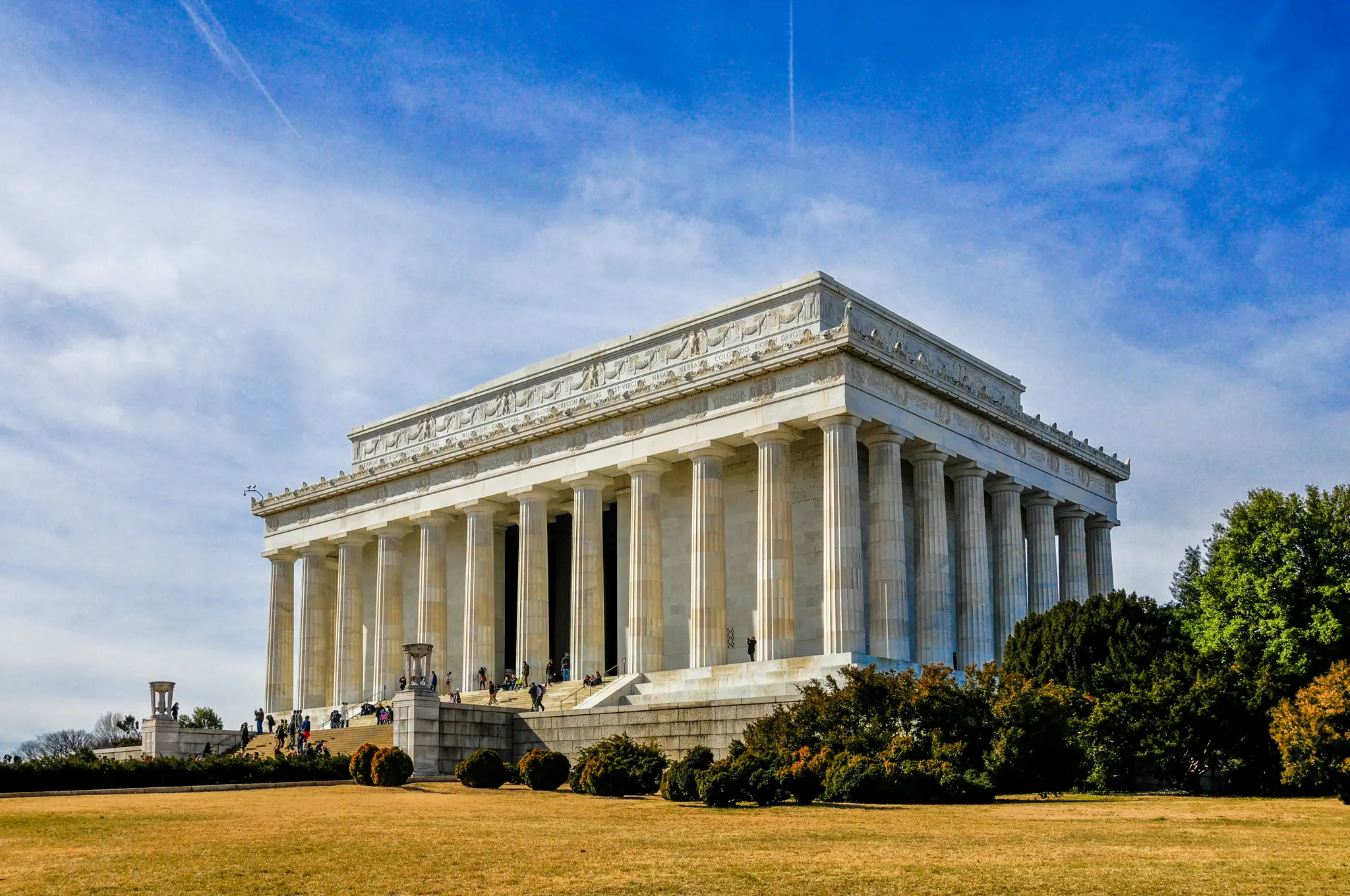 O imagine de ansamblu a Memorialului Lincoln, o clădire neoclasică albă, grandioasă, cu multe coloane, sub un cer albastru