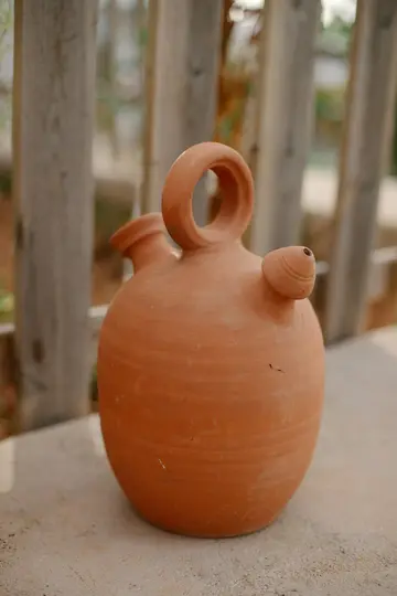 Un tradizionale botijo in terracotta, un recipiente per bere spagnolo, si trova su una superficie di pietra chiara con uno