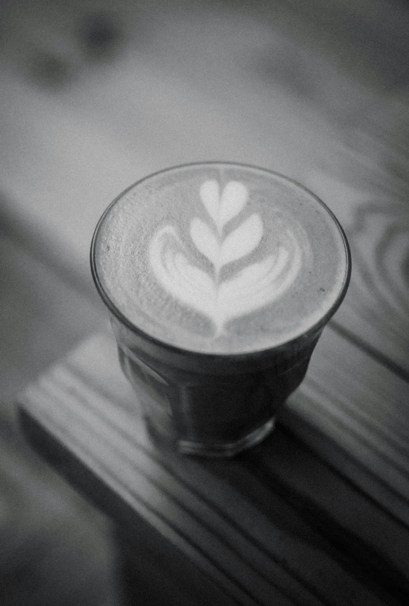 Čiernobiele detailné zábery latte v priehľadnom pohári s detailným dizajnom latte art v tvare srdca navrchu...