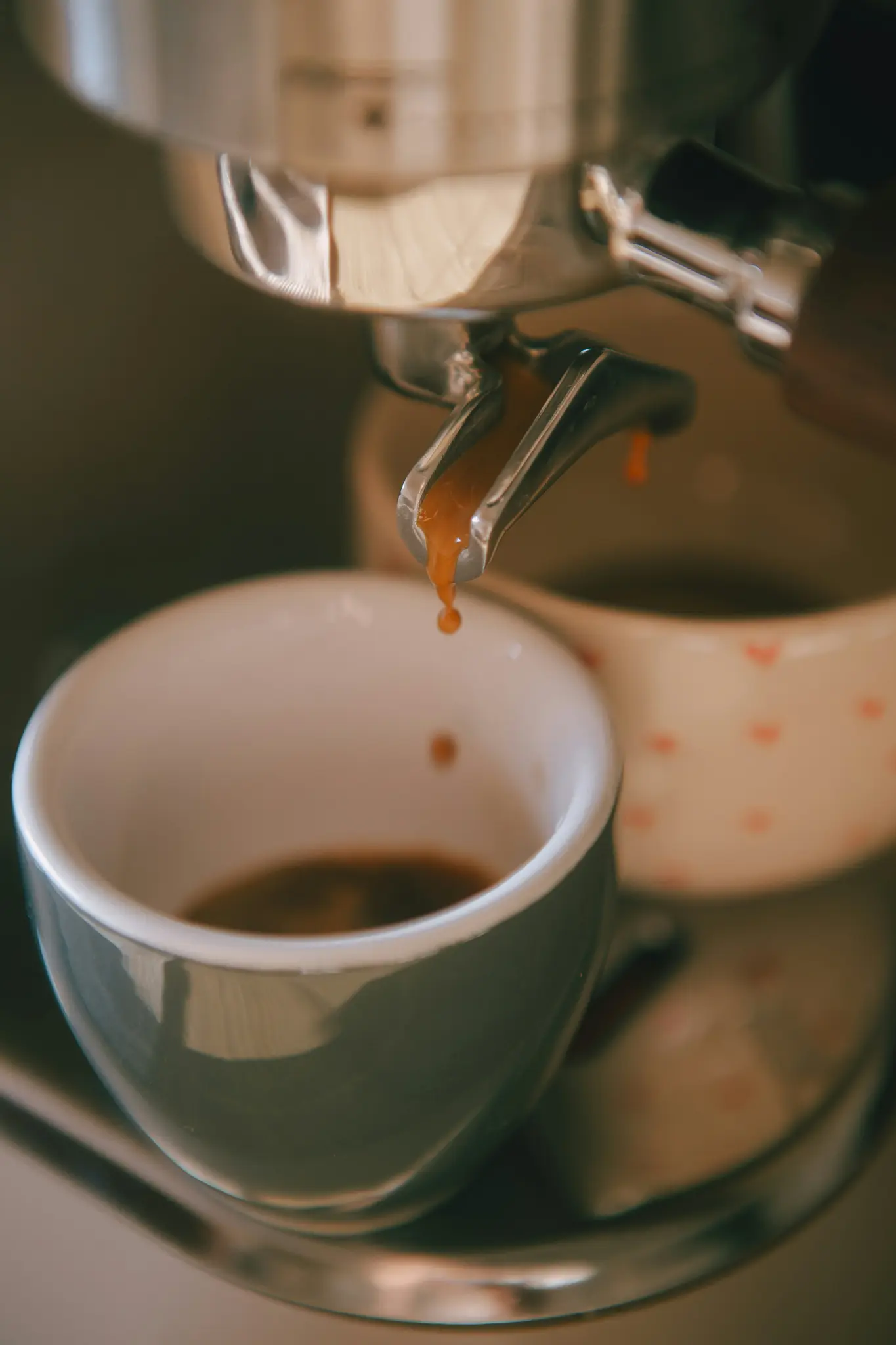 Een close-up van een koffiezetapparaat dat espresso zet in een grijze keramische mok, met druppende koffiedruppels.