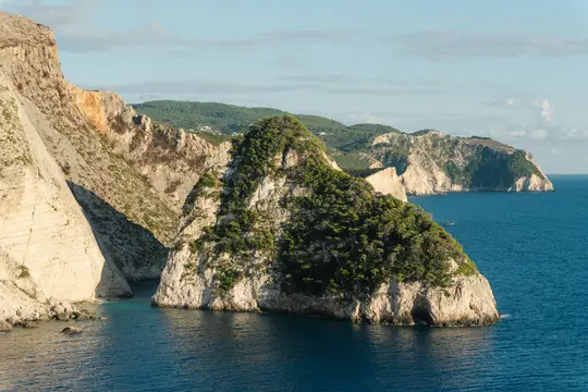 Un'ampia inquadratura del paesaggio mostra scogliere frastagliate e chiare sulla sinistra, con un'isola prominente ricoperta