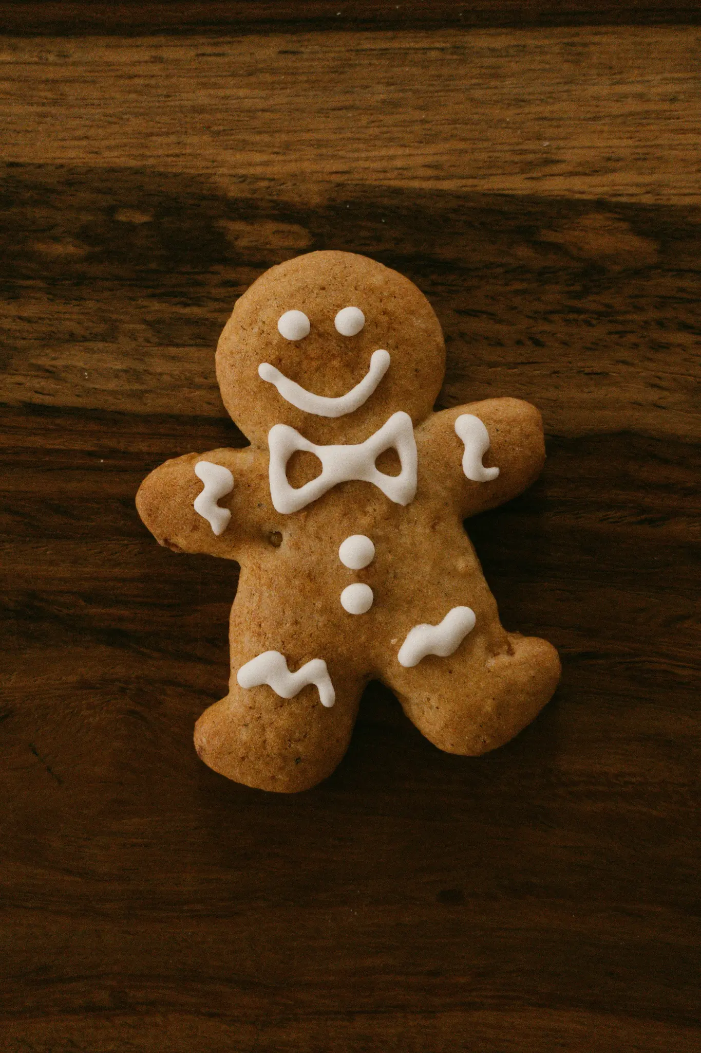 Una galleta de hombre de jengibre con glaseado blanco para los ojos, una sonrisa, pajarita, botones y puños ondulados