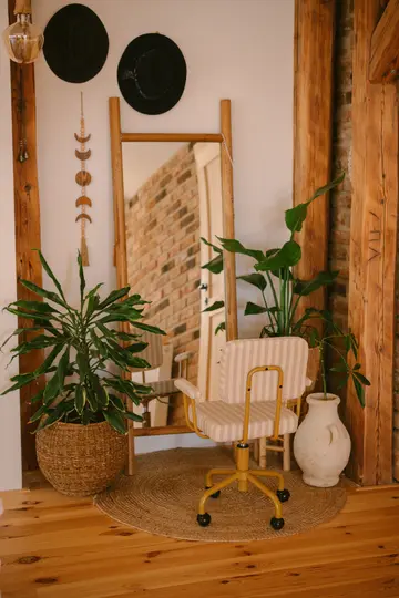 Una stanza accogliente con uno specchio a figura intera che riflette un muro di mattoni, una sedia da ufficio gialla e varie