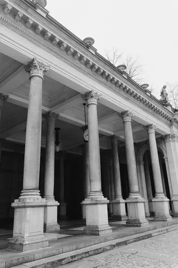 Una foto in bianco e nero, in basso angolo, di una classica colonnata con più colonne alte, un trabeazione ornata e una