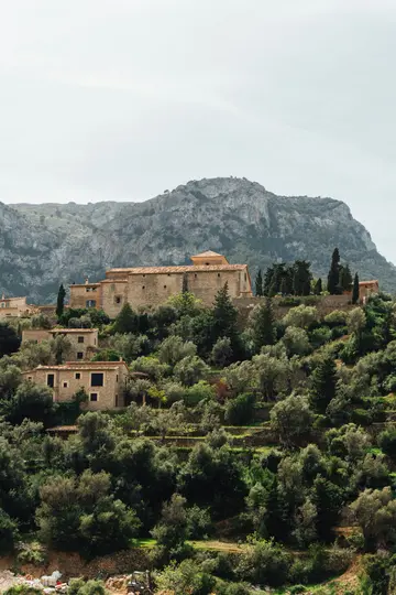 Un pittoresco villaggio con case tradizionali in pietra e tetti di tegole rosse è costruito su un rigoglioso pendio verde