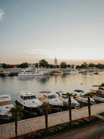 Μια υπερυψωμένη θέα ενός λιμανιού την χρυσή ώρα, που δείχνει αρκετές λευκές βάρκες αγκυροβολημένες κατά μήκος μιας πέτρινης