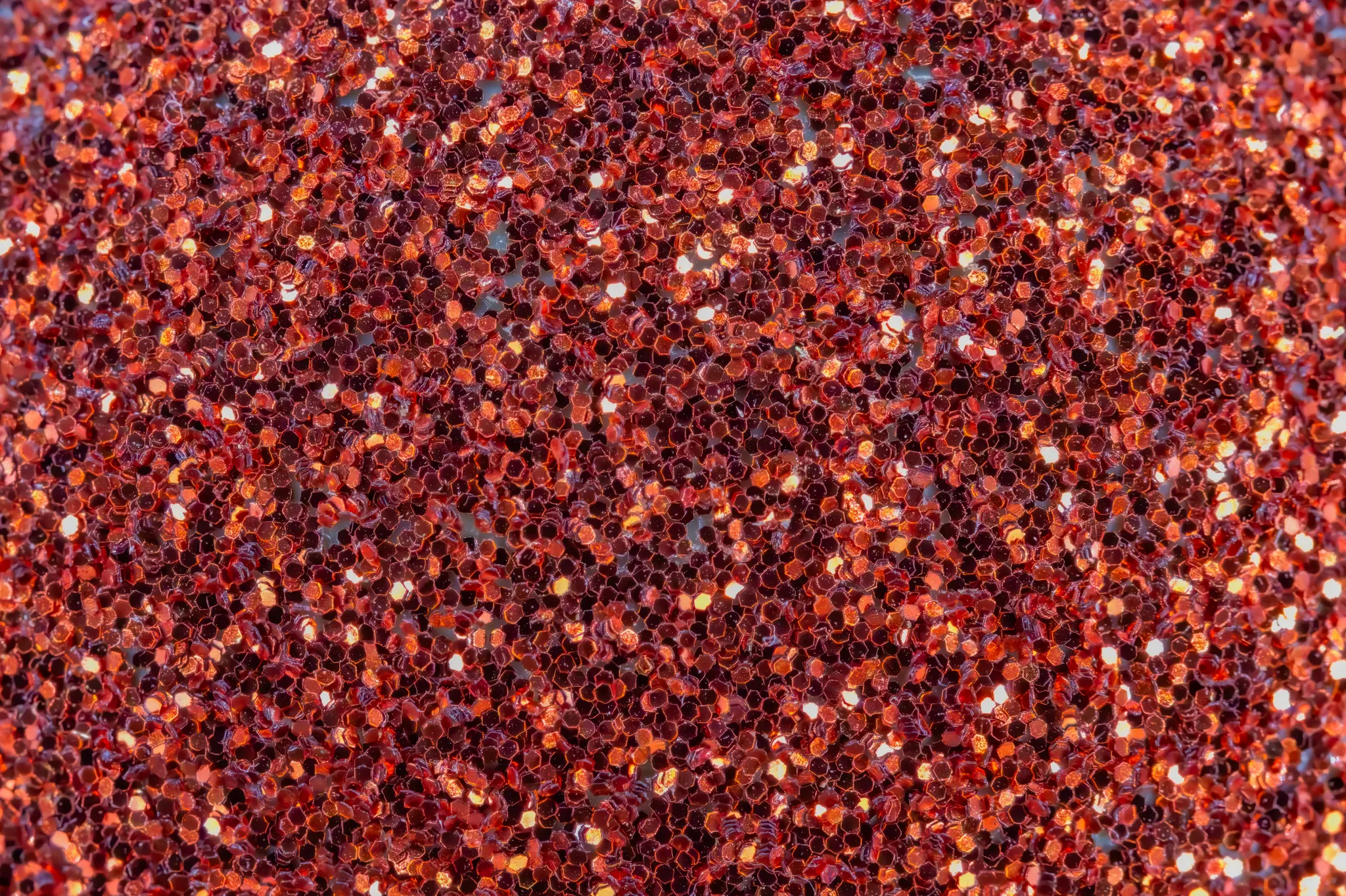 Gros plan macro de particules de paillettes rouges couvrant l'intégralité du cadre, montrant différentes nuances de rouge et