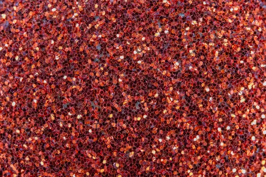 Makro detail červených trblietavých častíc pokrývajúcich celý rám, ukazujúci rôzne odtiene červenej a oranžovej s jasnými…