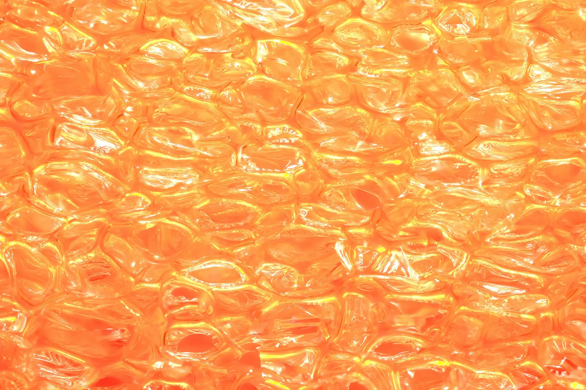 Un gros plan abstrait et vibrant d'une surface texturée translucide, orange et jaune, brillante avec des reflets vifs.