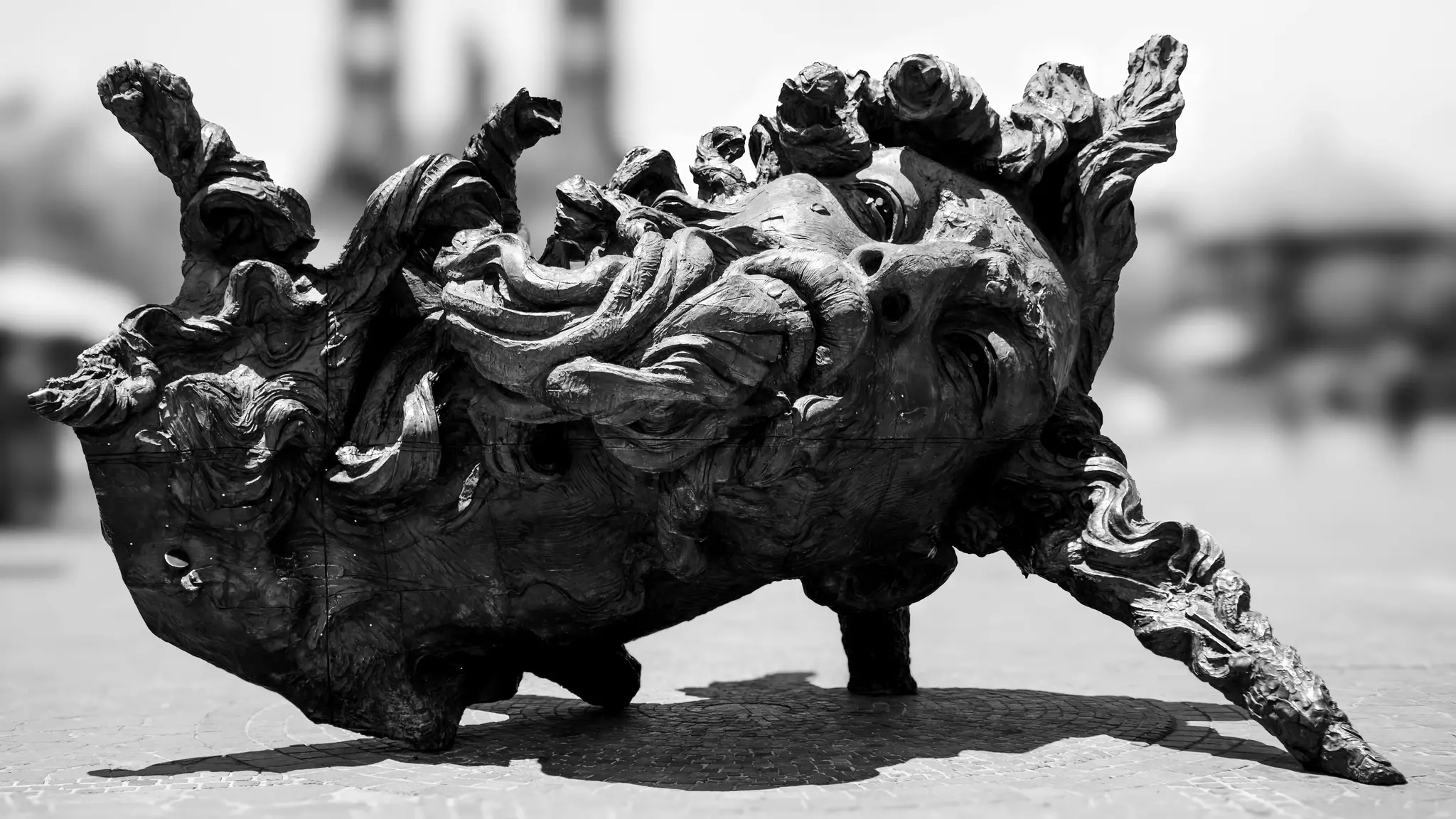 Une photo en noir et blanc d'une sculpture sombre et complexe avec un visage grotesque et des formes organiques