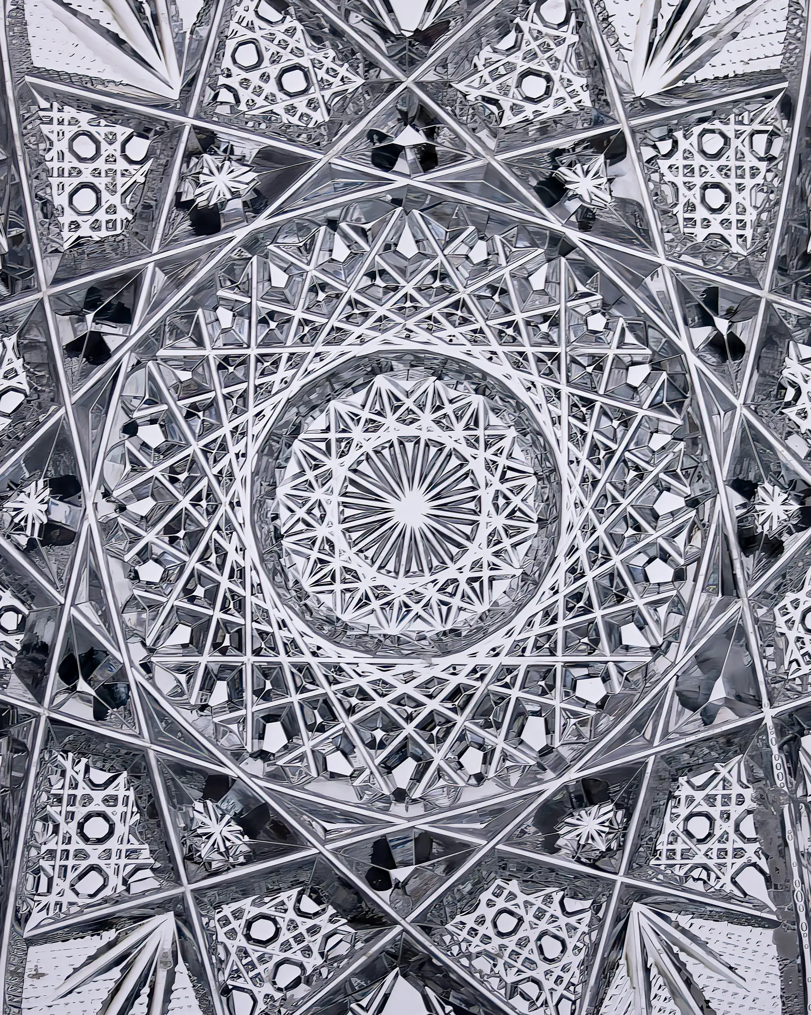 Gros plan, photo abstraite en noir et blanc de verre de cristal taillé, montrant des motifs géométriques complexes et