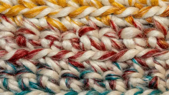 Une photo très rapprochée et détaillée de fil crocheté. Le fil est épais et texturé, avec des rangées de points visibles.