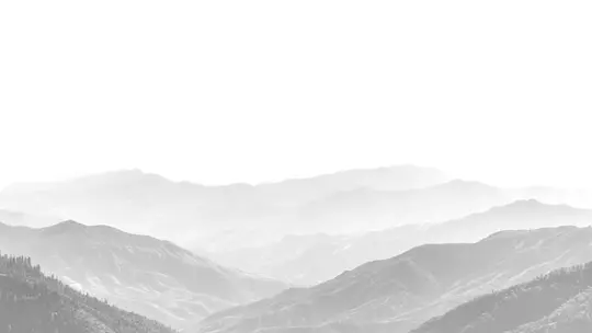 Crno-bijela pejzažna fotografija koja prikazuje nekoliko slojeva planina koje nestaju u maglovitom, svijetlo bijelom nebu.