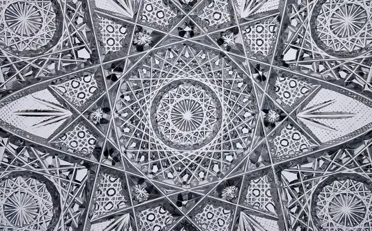 Un gros plan détaillé et symétrique d'un motif en verre taillé, présentant des lignes rayonnantes, des étoiles et des formes
