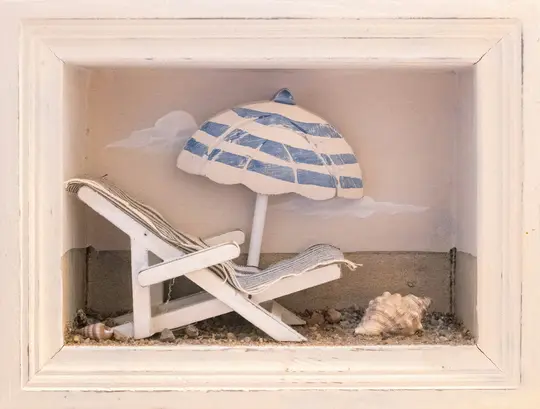 Miniatúrna plážová scéna v bielej drevenej krabici obsahuje biele lehátko s pruhovanou látkou, modro-bielu...