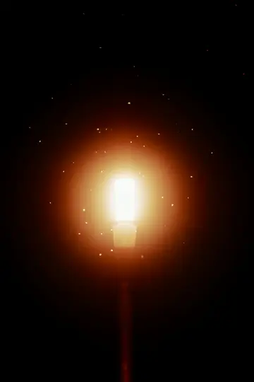 Kirkas, hohtava katuvalo erottuu täysin pimeää taustaa vasten, ja sitä ympäröivät lukuisat pienet, valaistut...