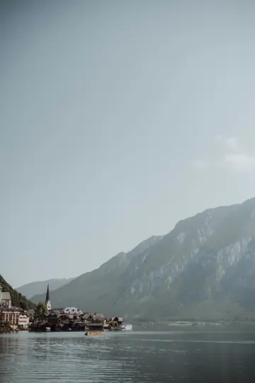 Una ripresa ampia di un pittoresco villaggio con un campanile prominente sulla riva di un lago tranquillo, con grandi