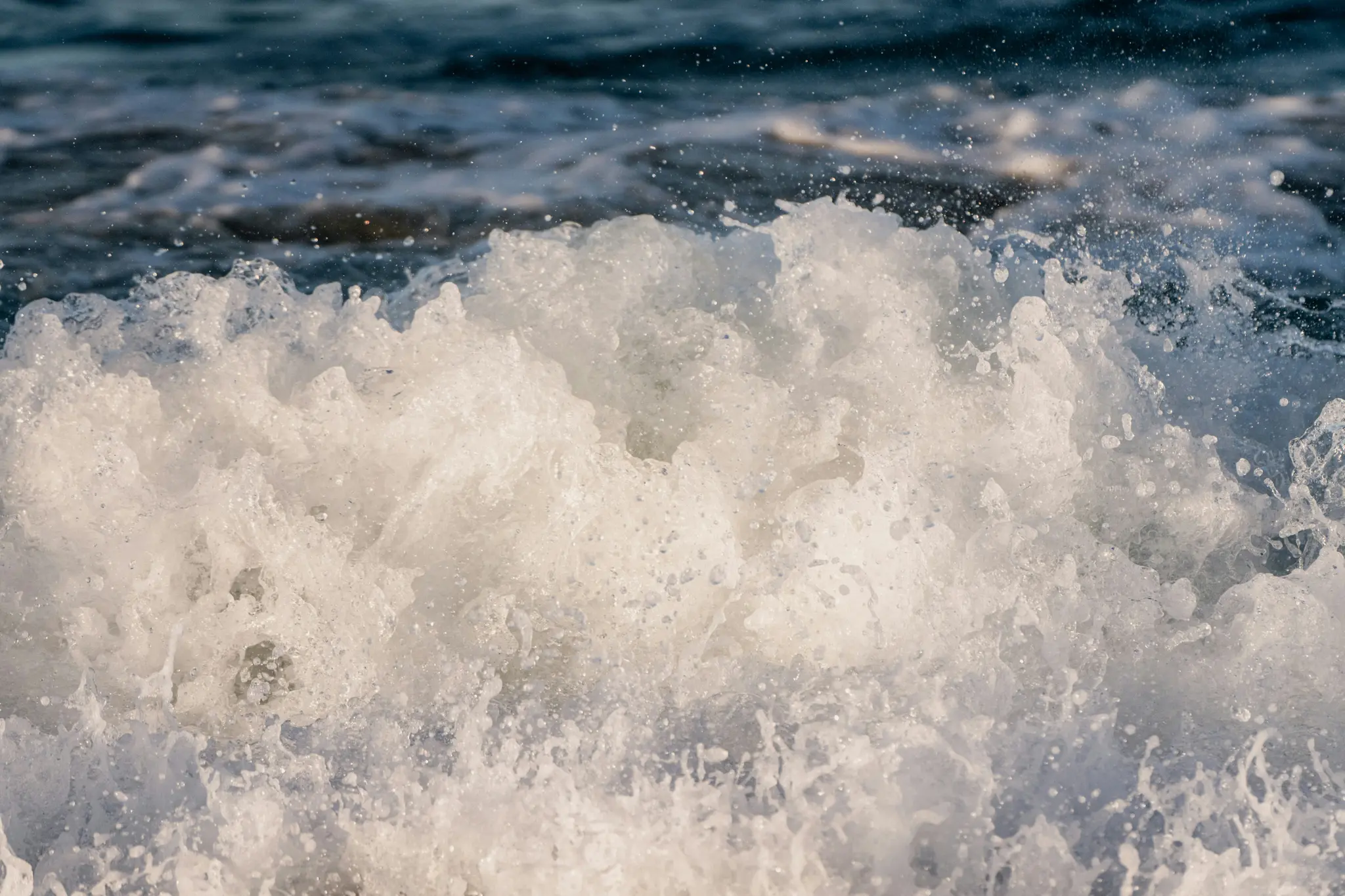 Een close-up van een krachtige, brekende oceaan golf, met wit schuimend water en talloze waterdruppels tegen een donkere