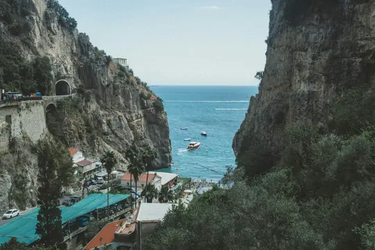 Una vista dall'alto di una città costiera con edifici e una strada costruiti in ripide scogliere, che si affaccia su un mare
