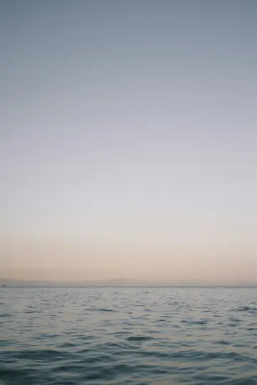 Una foto minimalista di un oceano calmo con leggere increspature, che incontra un cielo sfumato morbido che sfuma