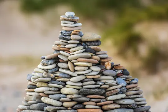 Ein großer Cairn, oder Steinhaufen, aus zahlreichen glatten, flachen, ovalen Steinen in verschiedenen Größen und Erdtönen.