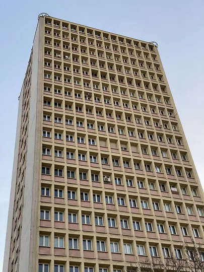 Egy nagyon magas, téglalap alakú épület, amelynek számos ablaka rácsos mintát alkot, bézs falakkal és rózsaszín díszítésekkel