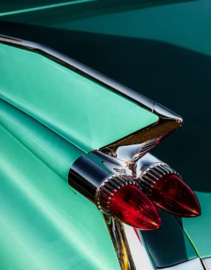 Detailní záběr z ptačí perspektivy na zadní část vintage tyrkysového vozu s výrazným zadním křídlem a dvěma červenými světly.
