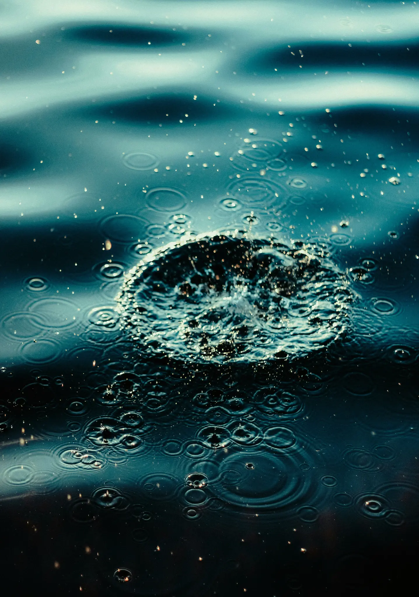 Un primo piano, ripresa dall'alto di una superficie d'acqua che mostra uno schizzo centrale che crea increspature e molte